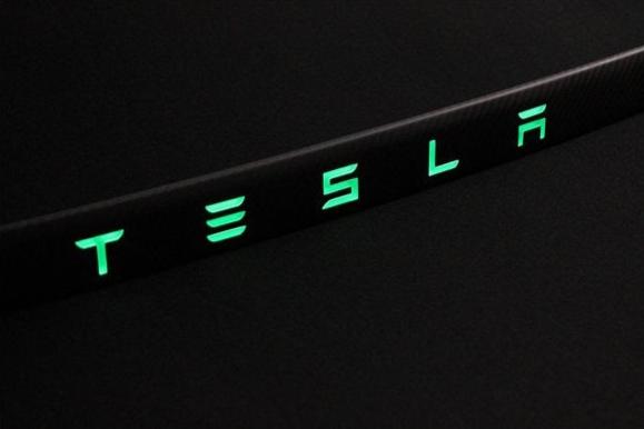 Carbon rear trunk trim with LEDs for Tesla Model S from Tuning Shop, made of genuine carbon fiber with a grey gloss UV-resistant coating.