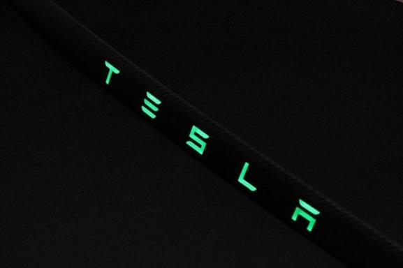 Carbon rear trunk trim with LEDs for Tesla Model S from Tuning Shop, made of genuine carbon fiber with a grey gloss UV-resistant coating.