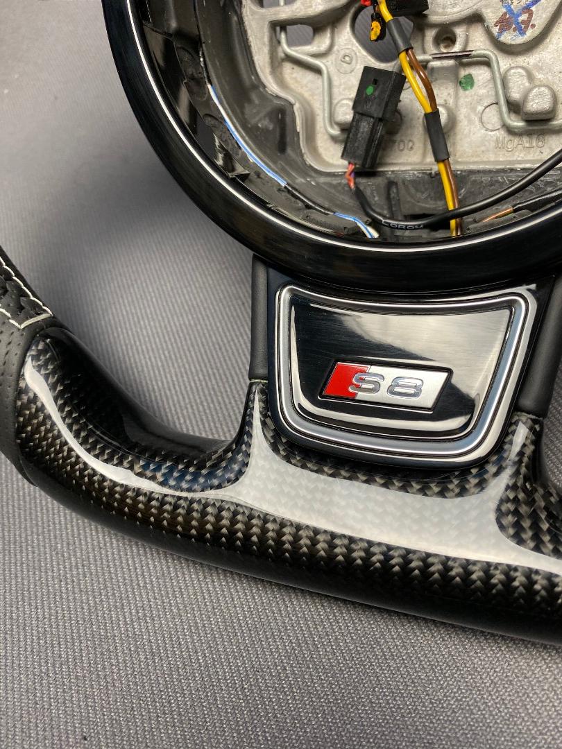 OEM remanufactured Audi S8 steering wheel with carbon fiber, perforated black leather, flat bottom, and piano black center from Tuning Shop.